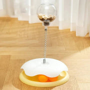 Yellow Interactive Cat Toy & Feeder Set with white top and orange balls, placed on wooden floor for indoor cat enrichment.